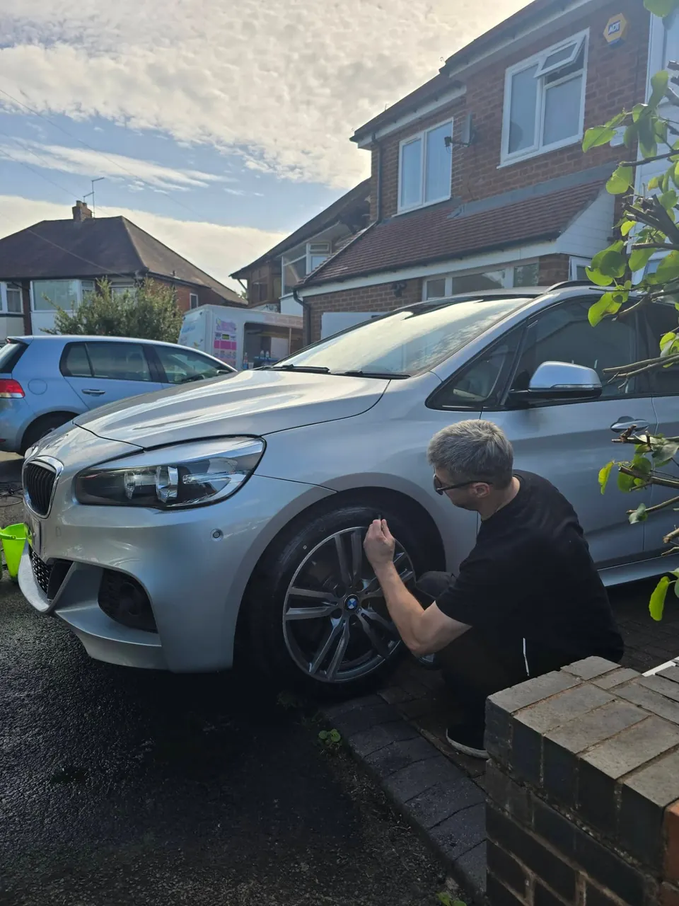 Riyaz cleaning the alloy wheel of the silver BMW 2 Series during a Sunday valet