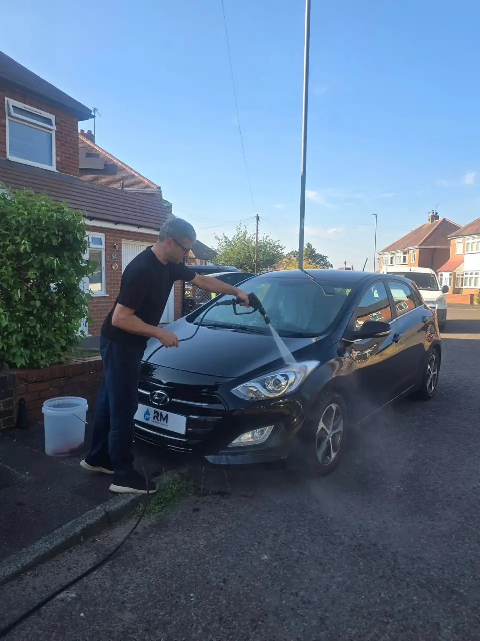 Riyaz pressure washing the windscreen of the black Hyundai i30 during a Gold valet
