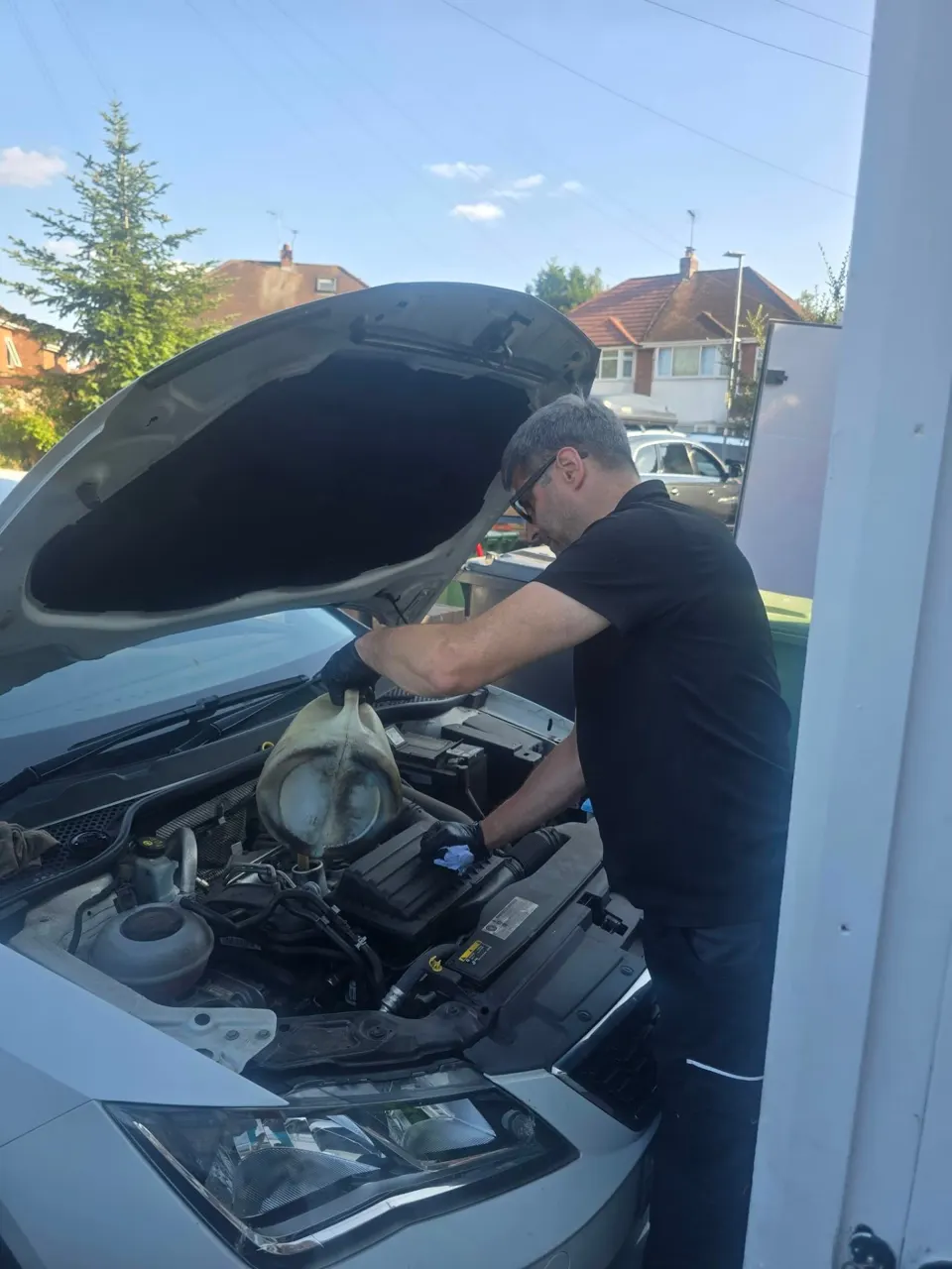 Riyaz pouring fresh engine oil into the Seat during an oil service