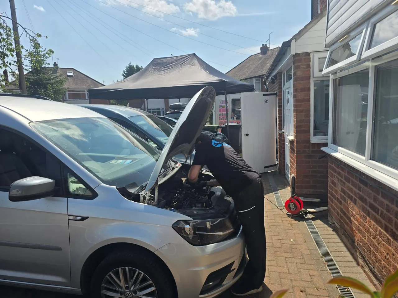 Side view of Riyaz working in the VW Caddy engine bay